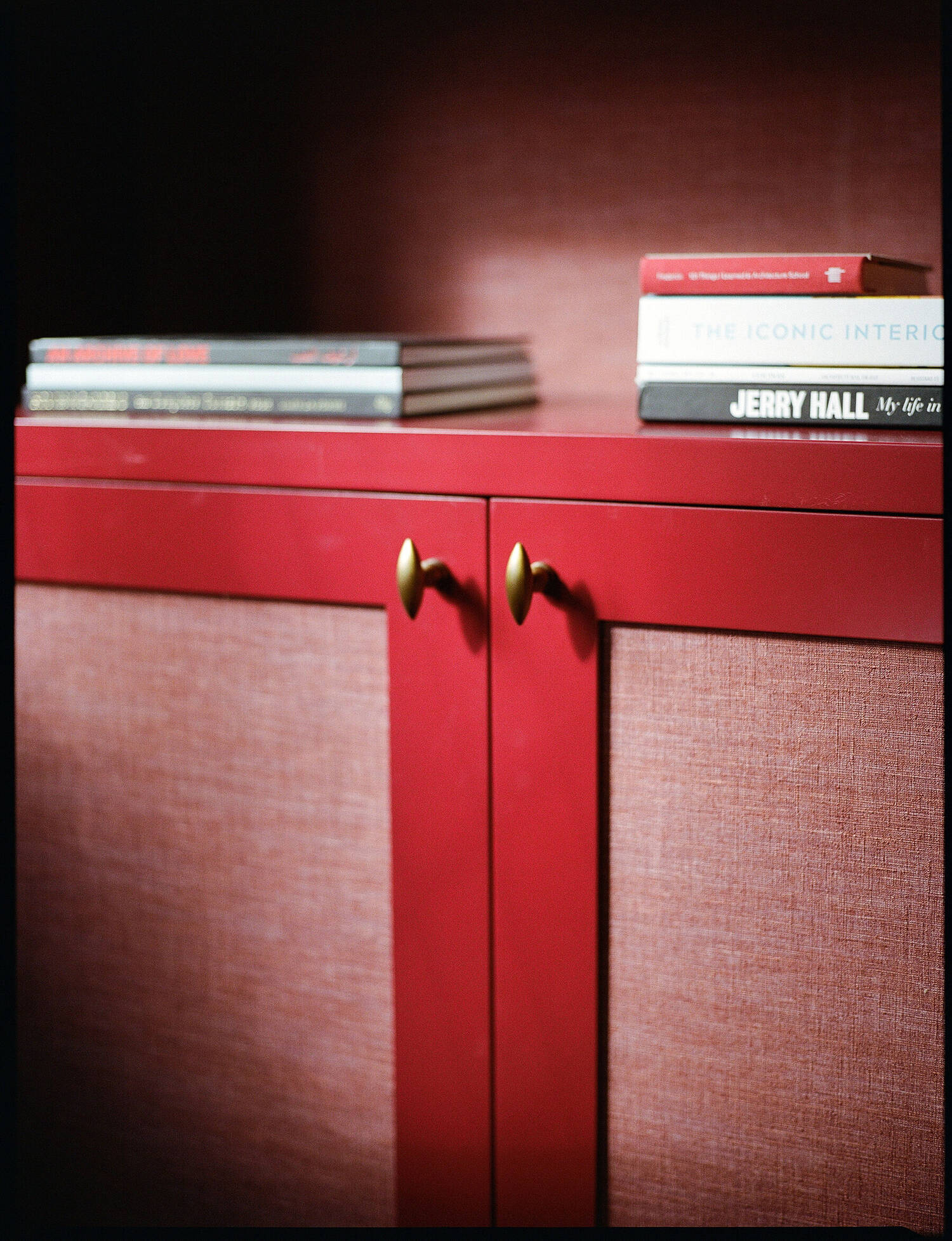 Linen-panelled cabinet doors in red lacquer