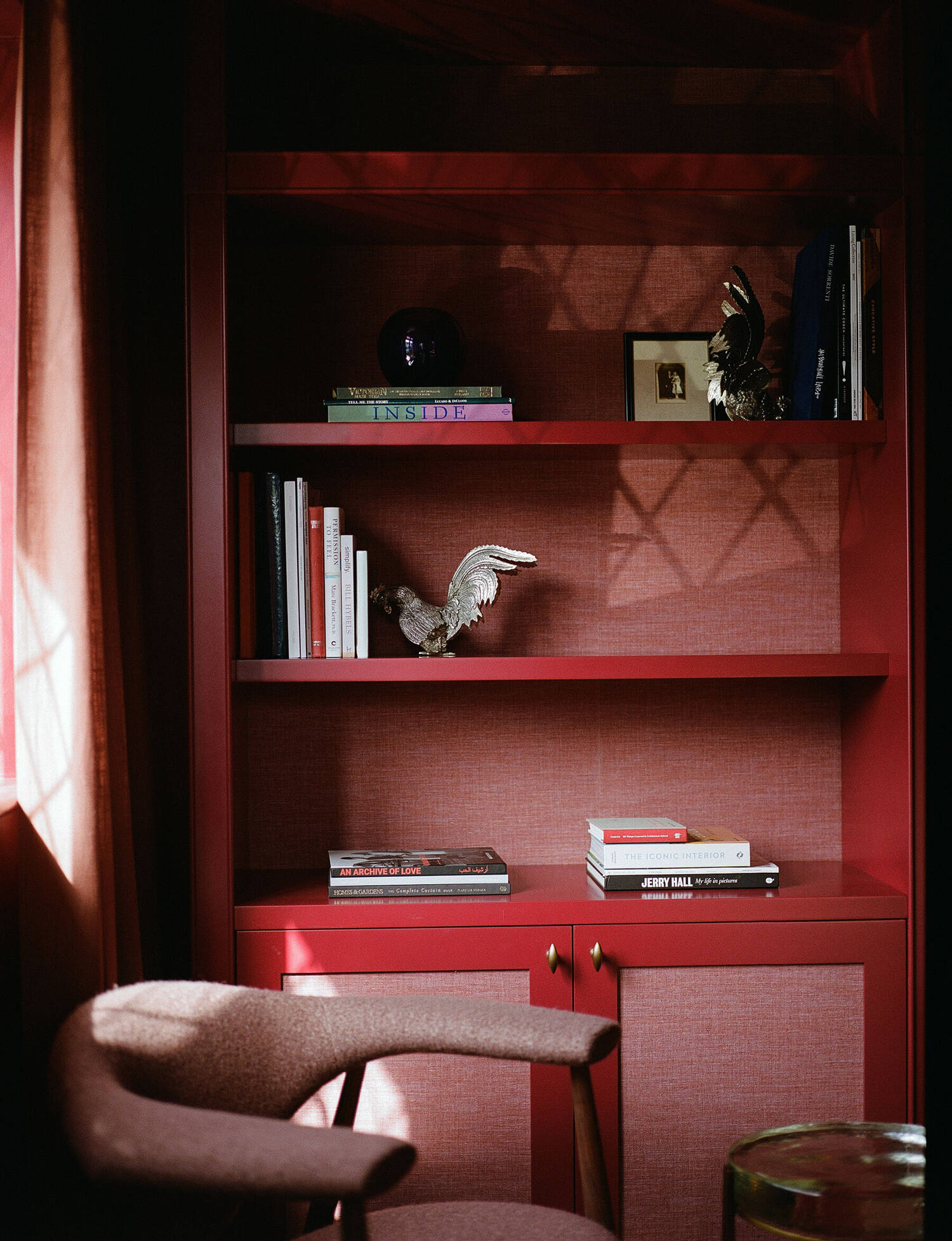 Red bookcase with quilted back panel and wool armchair