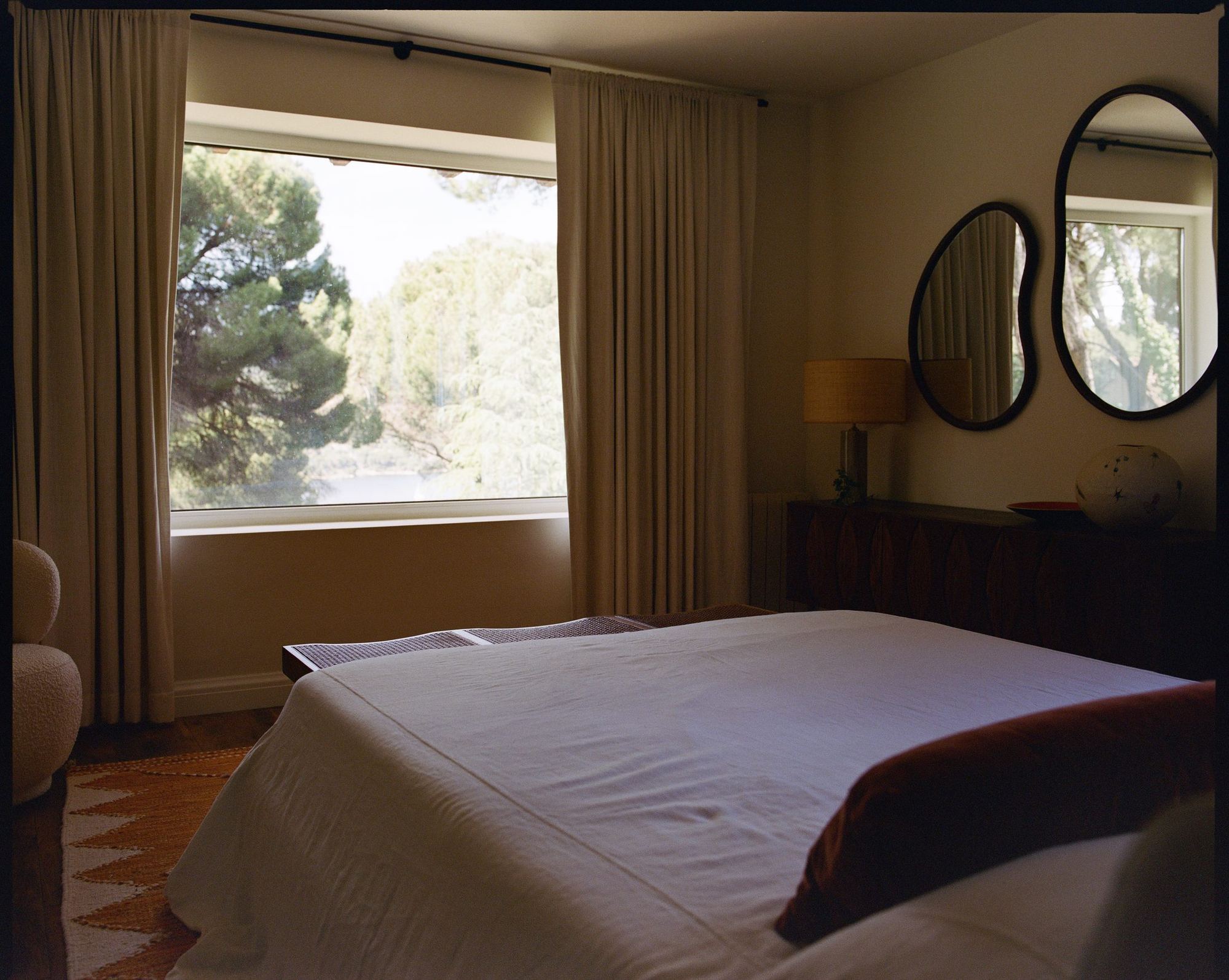 Bedroom with kidney-shaped mirrors and pine views