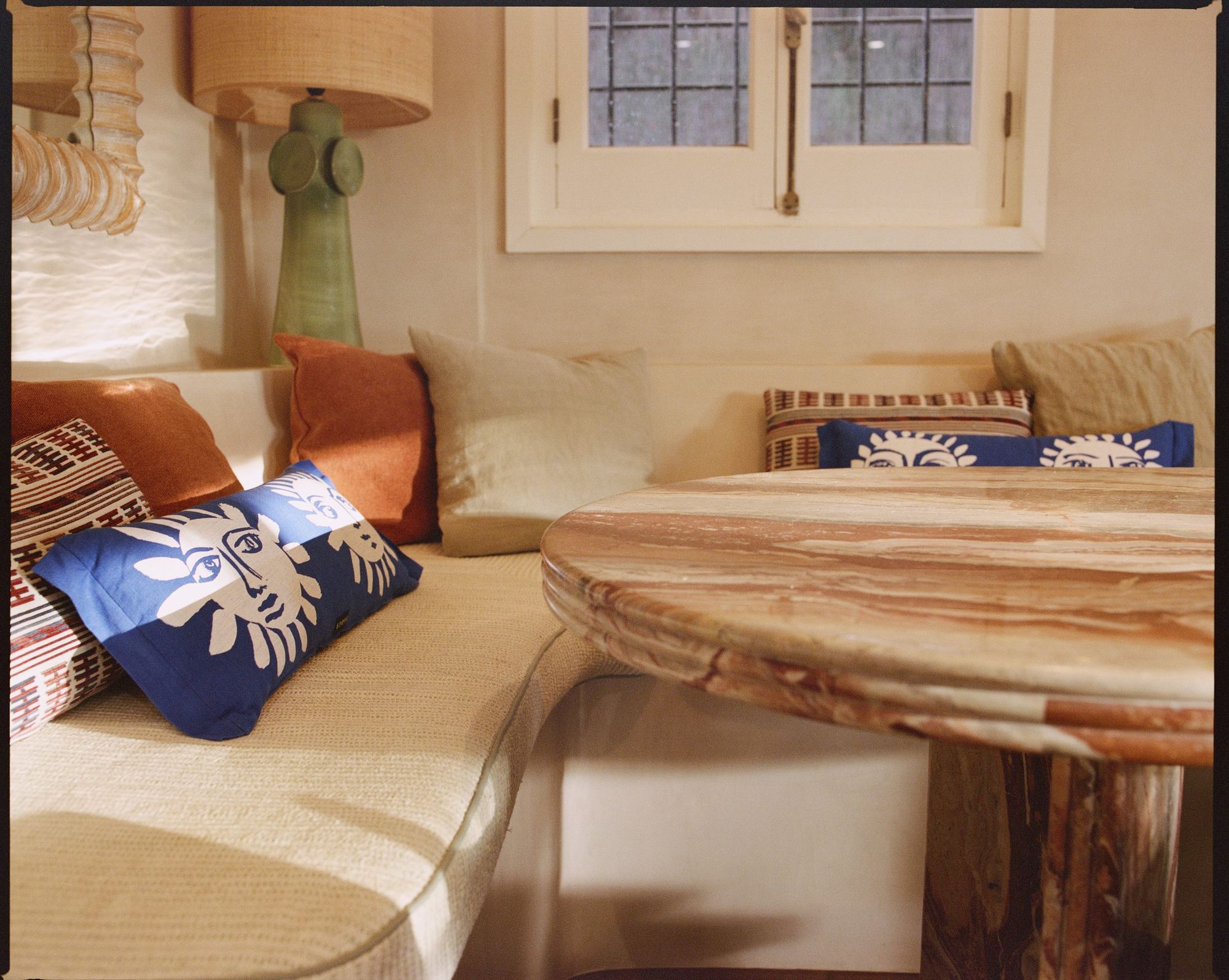 Cushioned window seat with patterned bolsters and a marble table
